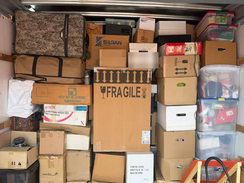 Boxes, suitcases and totes stacked floor to ceiling in a rental truck on one of our jobs, with a box marked fragile upright in the middle.